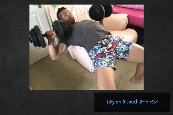 Bench press at home without a bench by using a couch armrest.